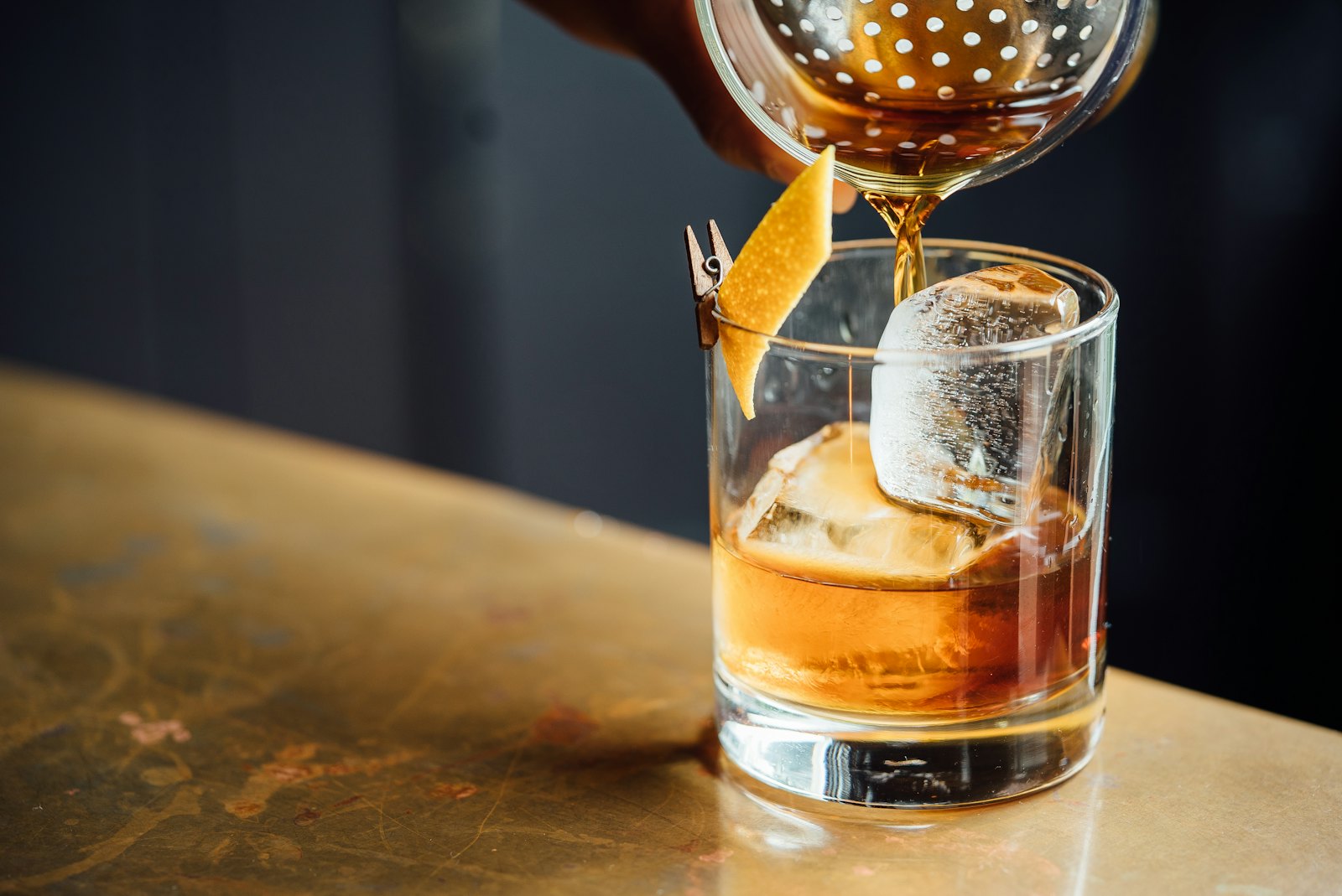 Drink sendo servido em copo baixo com gelo e casca de laranja